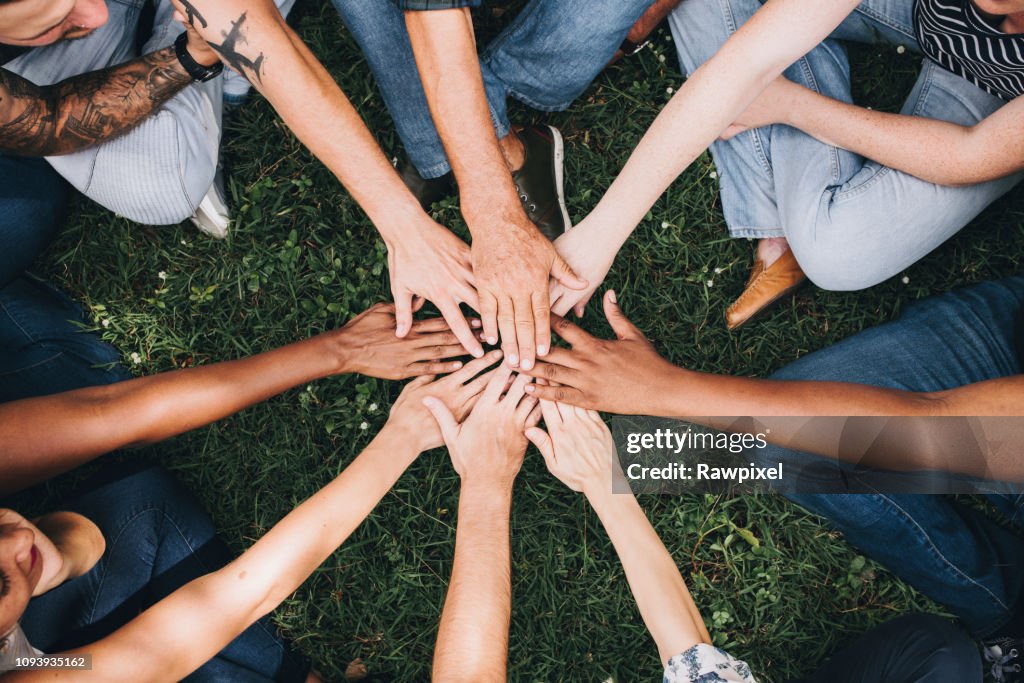 People stacking hands together in the park