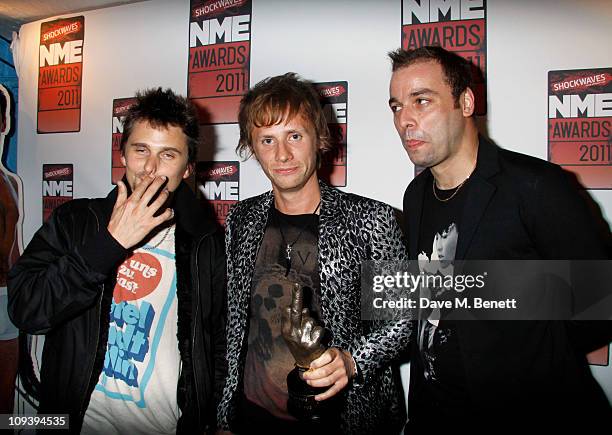 Matt Bellamy, Dominic Howard and Christopher Wolstenholme of the band Muse pose with the "Best British Band award supported by Shockwaves" in front...