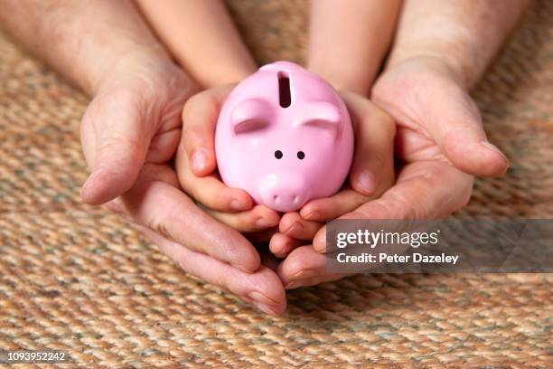 father and child holding piggy bank - genderblend fotografías e imágenes de stock