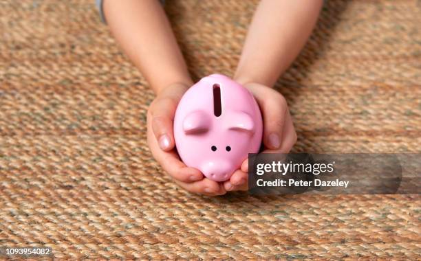 piggy bank being cradled in child's hands - zakgeld stockfoto's en -beelden