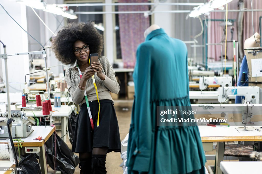 Female designer with tape measure using phone