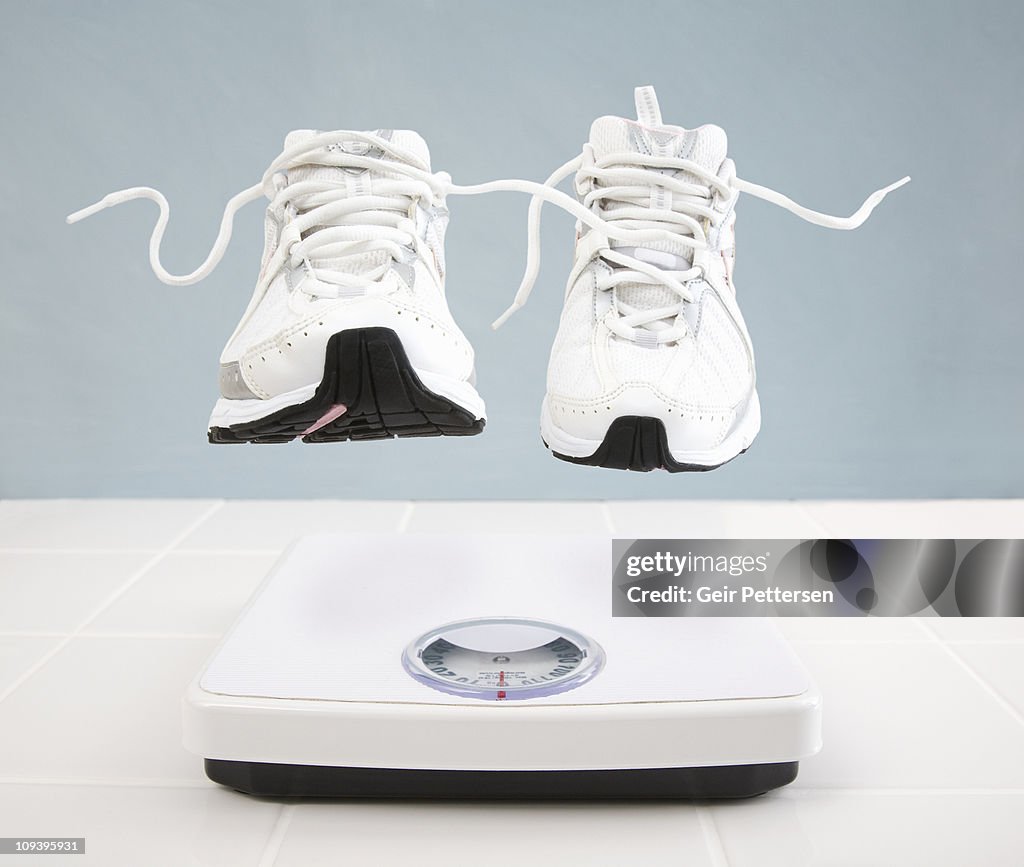 Running shoes hovering above bathroom scale