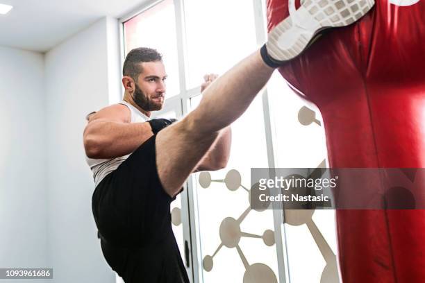 fighter punching bag in gym - kickboxing stock pictures, royalty-free photos & images