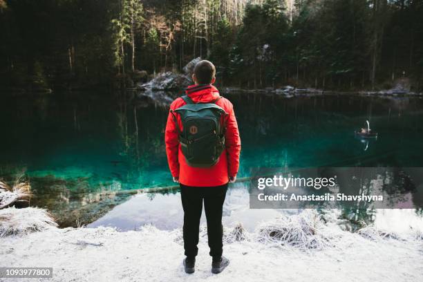 man with backpack walking at lake blausee in switzerland - mitholz stock pictures, royalty-free photos & images