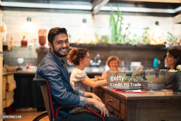 hispanic-latino-familie mahlzeit zu hause - junger mann lächelnd, blick in die kamera - sitting at table looking at camera stock-fotos und bilder