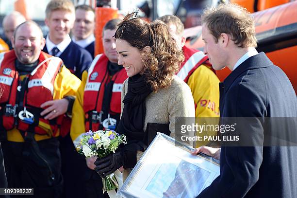 Britain's Prince William accompanied by his fiancee Kate Middleton receive gifts during a visit to a RNLI Lifeboat Station in Anglesey, near Bangor...