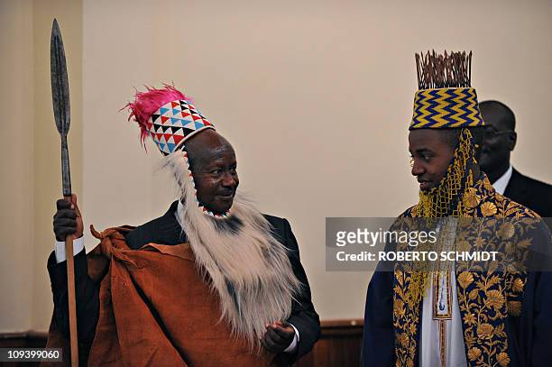 Ugandan President Yoweri Museveni wearing traditional Toroo kingdom ceremonial head gear smiles at Ugandan King Oyo Nyimba Kabamba Iguru Rukidi IV...