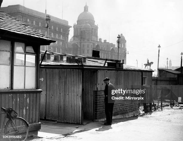 In the background the stately Dock Board building. In the foreground a corner of Liverpool's show place - the Pier Head. Shanties, barbed wire,...