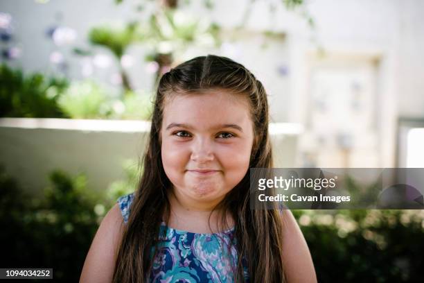 portrait of cute girl smiling while standing at park - chubby kid stock-fotos und bilder