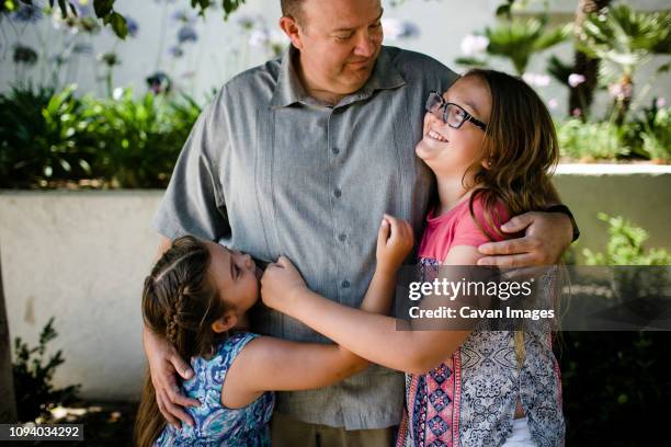 happy daughters embracing father while standing at park - chubby kid stock-fotos und bilder