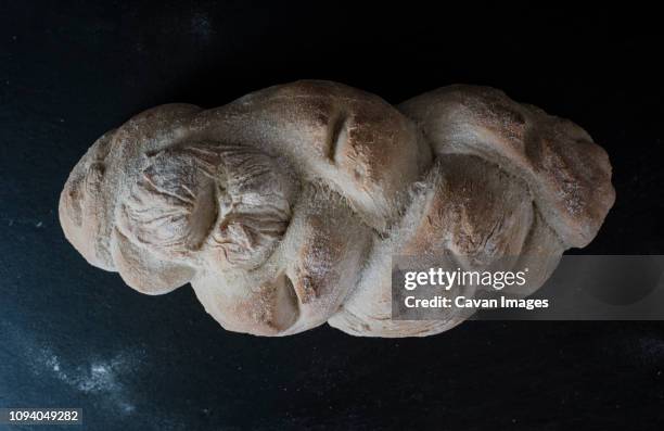 overhead view of baked braided bread on slate at home - geflochtenes brot stock-fotos und bilder