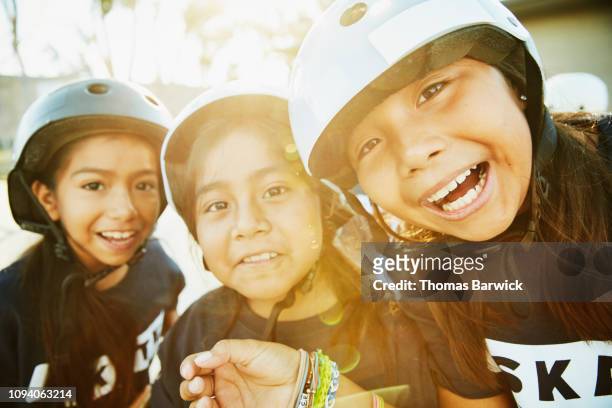 Portrait of smiling young female friends making faces during skateboarding camp