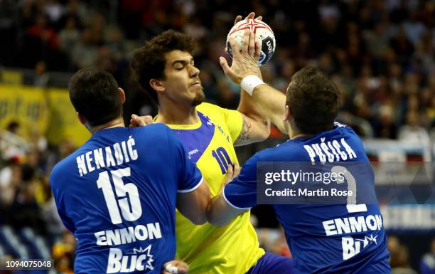 Drasko Nenadic and Milijan Pusica of Serbia challenge Jose Toledo of Brazil during the 26th IHF Men's World Championship group A match between Serbia...