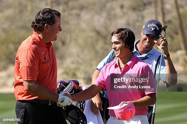 Phil Mickelson congrulates Rickie Fowler on his win on the 13th hole as caddie Jim 'Bones' Mackay looks on during the second round of the Accenture...