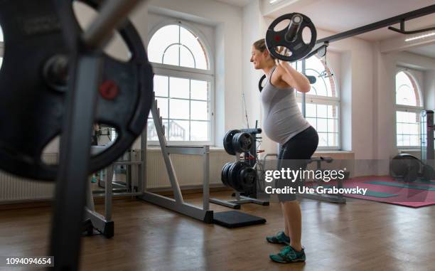 Bonn, Germany Young pregnant woman training in a gym, on January 24, 2019 in Bonn, Germany. The woman is eight months pregnant and is doing strength...