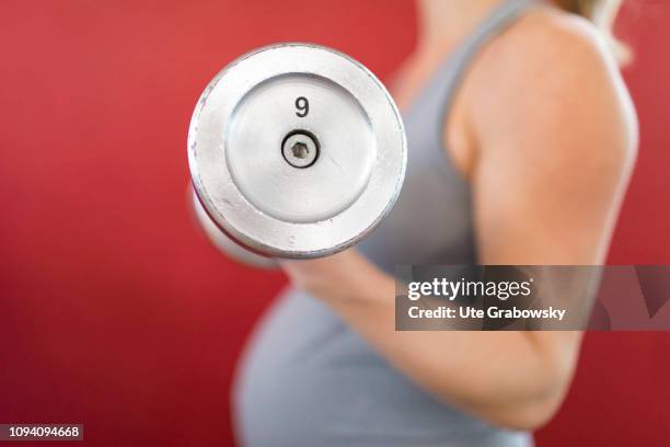 Bonn, Germany Young pregnant woman training in a gym, on January 24, 2019 in Bonn, Germany. The woman is eight months pregnant and is doing strength...