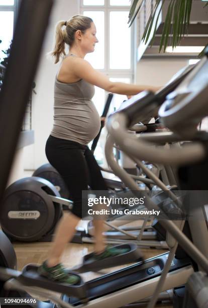 Bonn, Germany Young pregnant woman training in a gym, on January 24, 2019 in Bonn, Germany. The woman is eight months pregnant and is doing cardio...