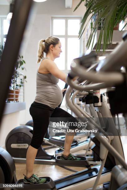Bonn, Germany Young pregnant woman training in a gym, on January 24, 2019 in Bonn, Germany. The woman is eight months pregnant and is doing cardio...