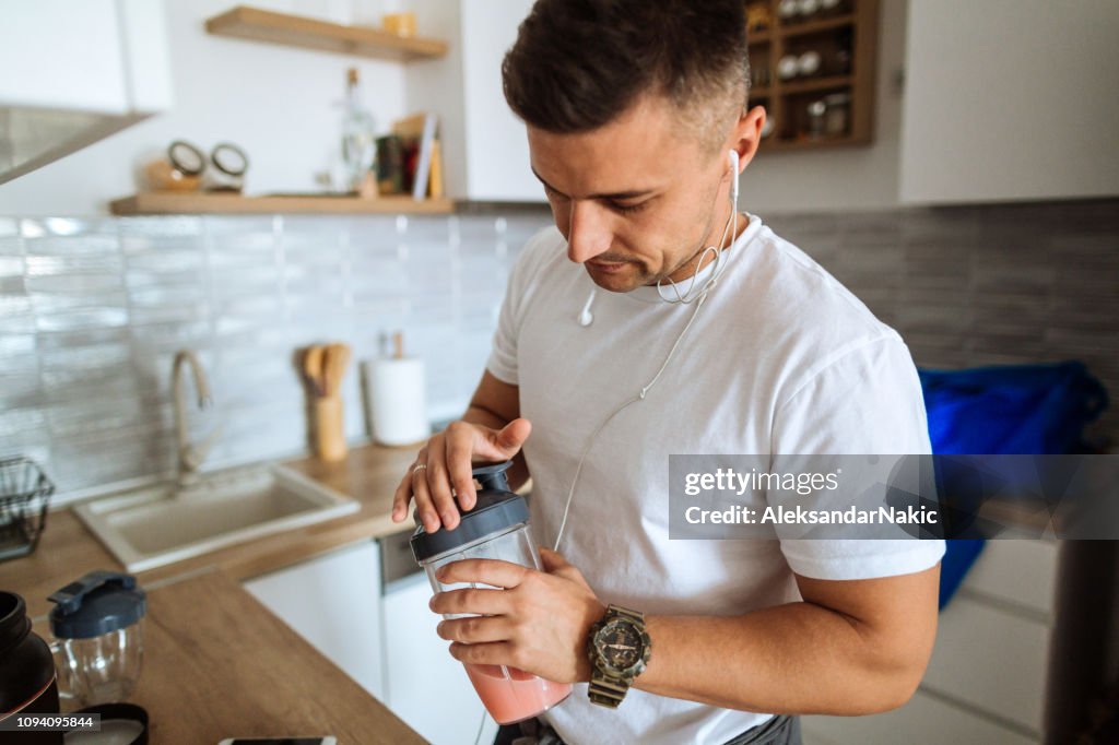 Young man making protein shake before training