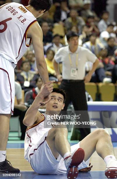 China's Yao Ming gets a helping hand from teammate Gong Xiaobin during a basketball match with the Philippine team at the 14th Asian Games in Busan,...