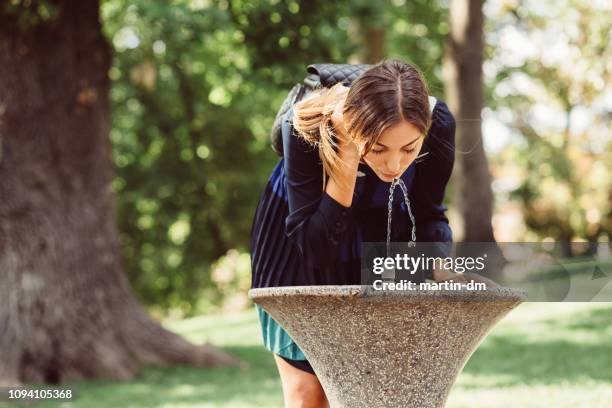 junge frau im park trinkwasser am heißen sommertag - wasserstrahl stock-fotos und bilder