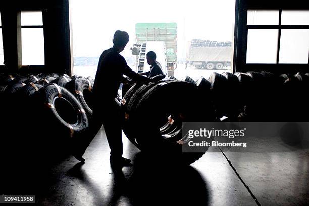 Factory workers roll tires through a warehouse at the Pirelli & C SpA tire factory in Jining, Shandong Province, China on Thursday, Feb. 24, 2011....