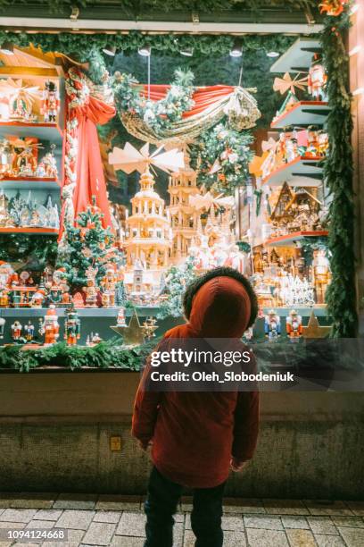 kleiner junge auf weihnachten schaufenster betrachten - window shopping stock-fotos und bilder