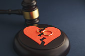 Wedding rings on the figure of a broken heart from a tree, hammer of a judge on a wooden background. Divorce