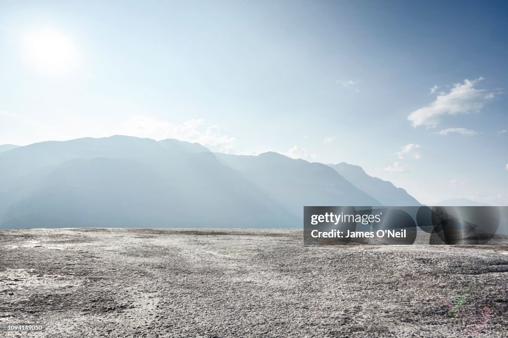 Flat rocky plateau with distant mountains and sunlight