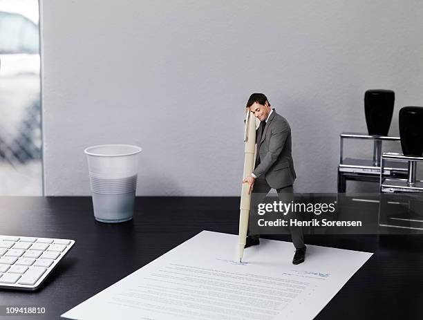 small businessman signing document on office desk - little big man photos et images de collection