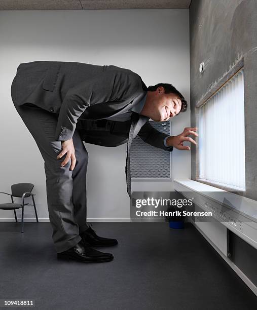giant businessman looking out of window - gluren stockfoto's en -beelden