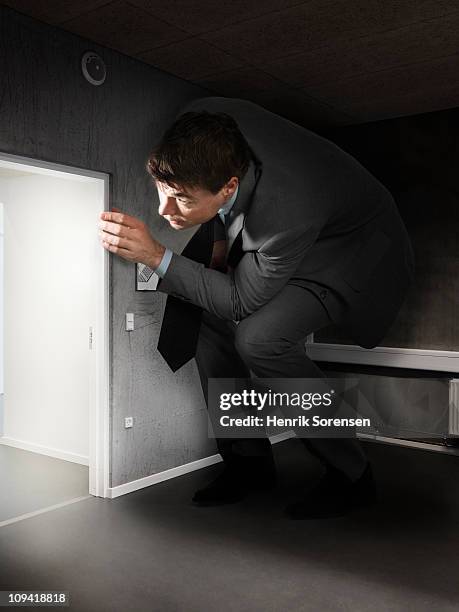 oversized businessman peeking around a corner - couvert stock pictures, royalty-free photos & images