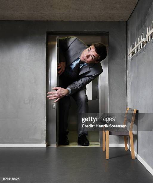 oversized businessman in an elevator - géant photos et images de collection