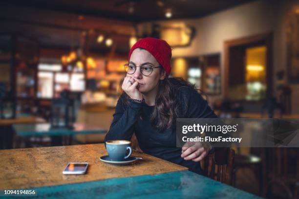 contemplating student sitting at a coffee shop - holiday sadness stock pictures, royalty-free photos & images