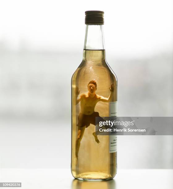 adult male swimmer inside capped glass bottle - drowning stock-fotos und bilder