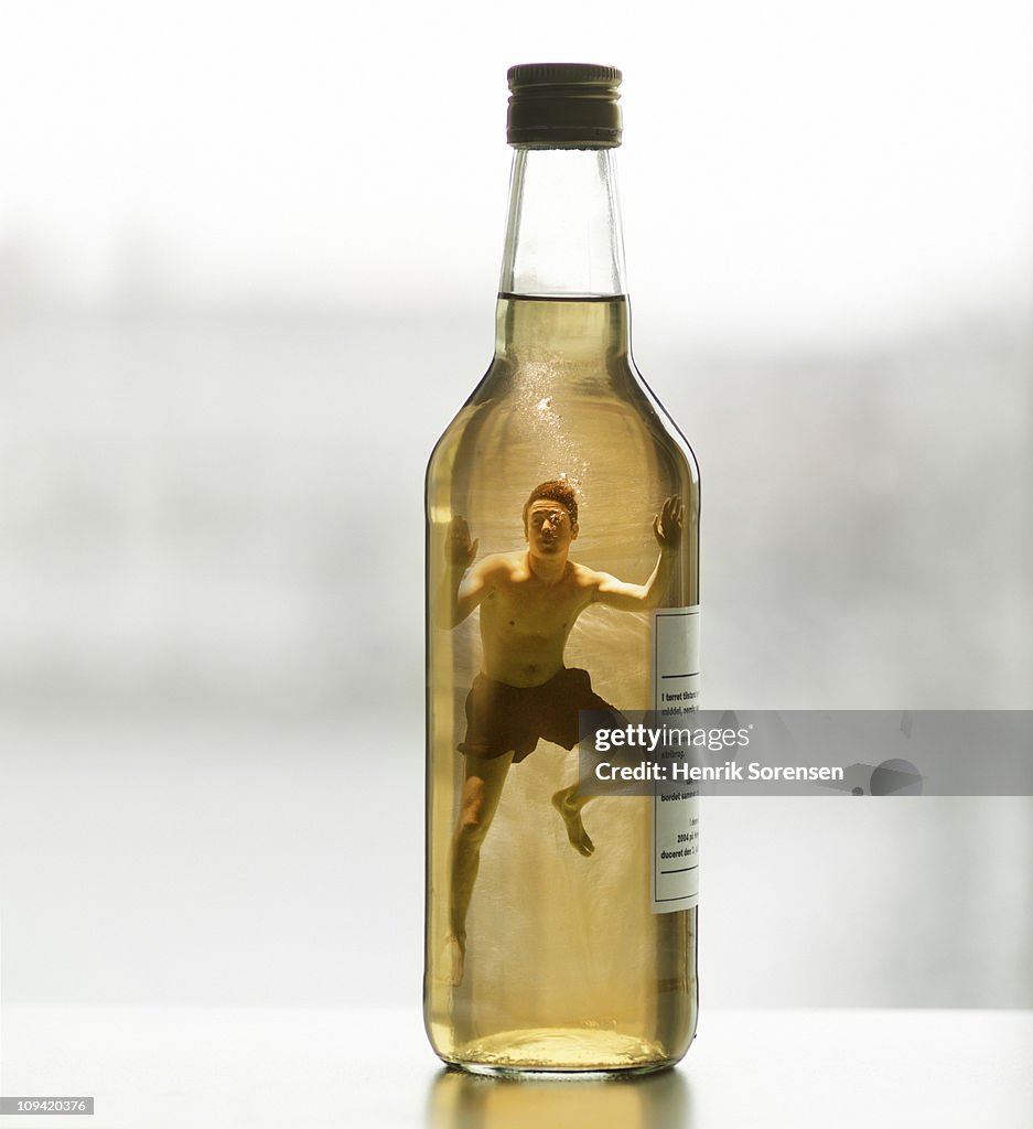 Adult male swimmer inside capped glass bottle