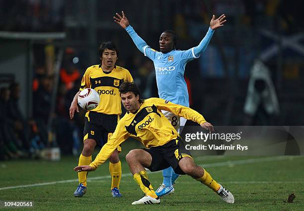 Juan Carlos Toja and his team mate Daisuke Sakata of Aris battle for the ball with Shaun Wright-Phillips of Machester City during the first leg round...