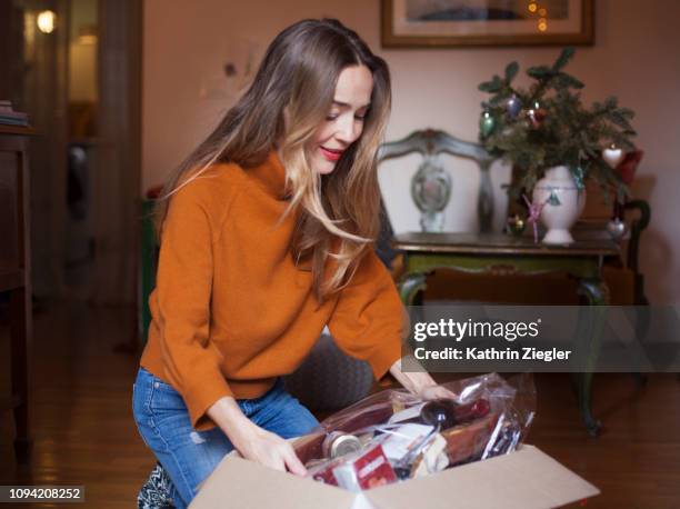 woman unpacking christmas parcel at home - christmas gift boxes stock pictures, royalty-free photos & images
