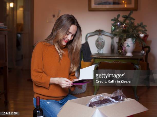woman unpacking christmas parcel at home, reading greeting card - wine home delivery stock pictures, royalty-free photos & images