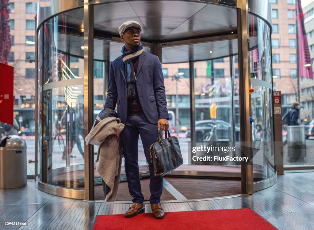 Handsome entrepreneur entering the mall through a revolving door