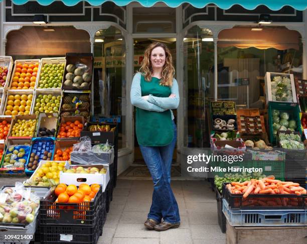 female grocer at shop entrance - magasin de fruits et légumes photos et images de collection