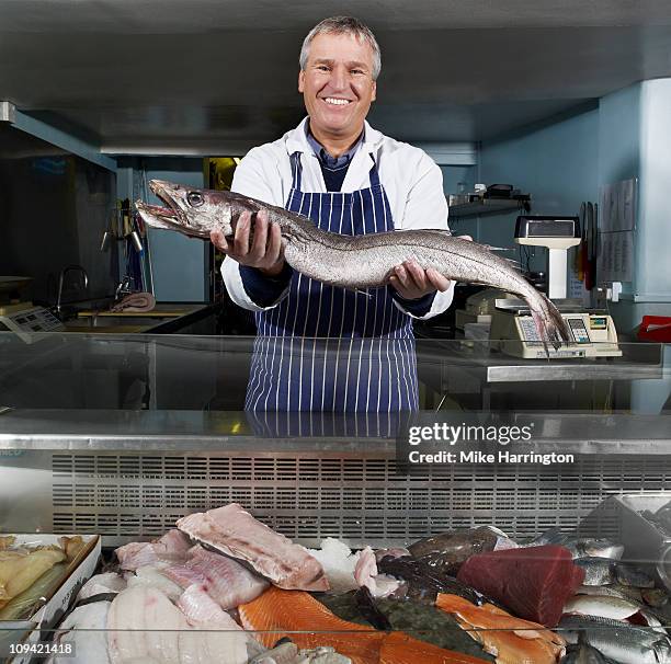 male fishmonger holding large fish - fishmonger stock pictures, royalty-free photos & images