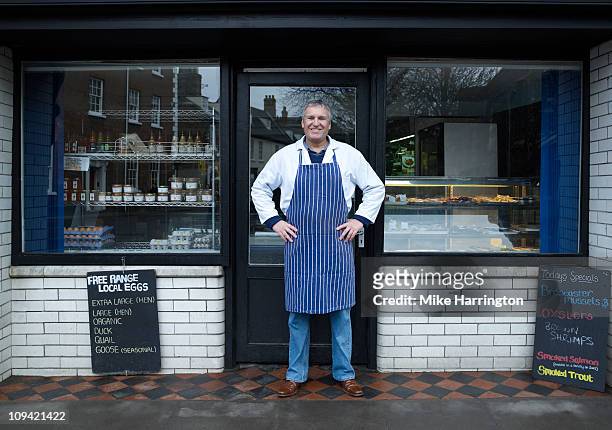 male fishmonger standing outside shop front - retail occupation stock-fotos und bilder