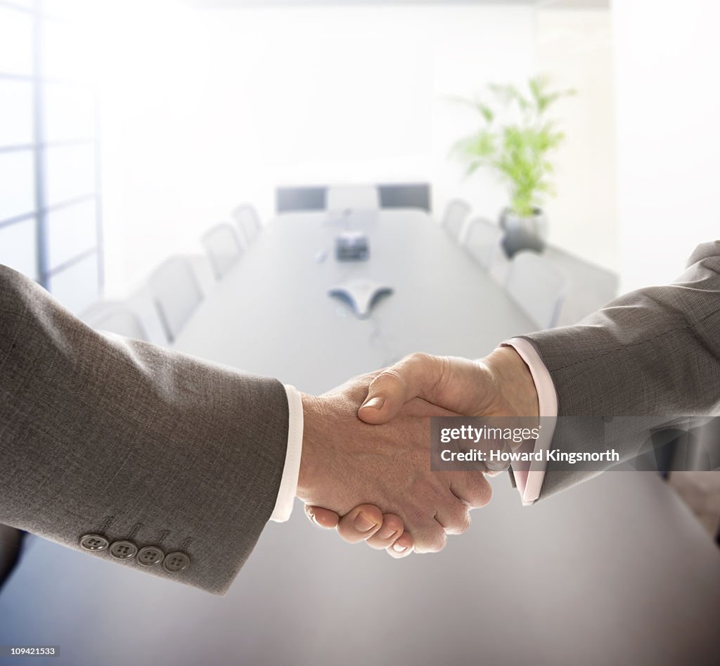 2 men shaking hands in a boardroom