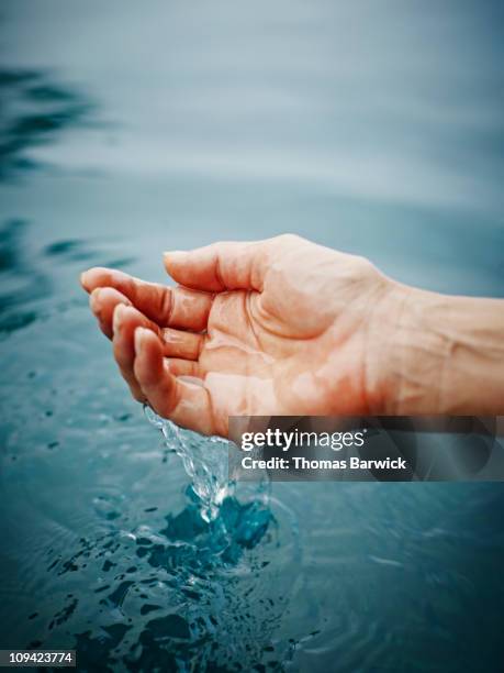 hand cupping water with droplets falling from hand - hand wasser stock-fotos und bilder