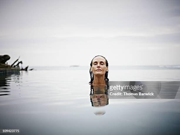 woman in infinity pool at tropical resort - break through stock pictures, royalty-free photos & images