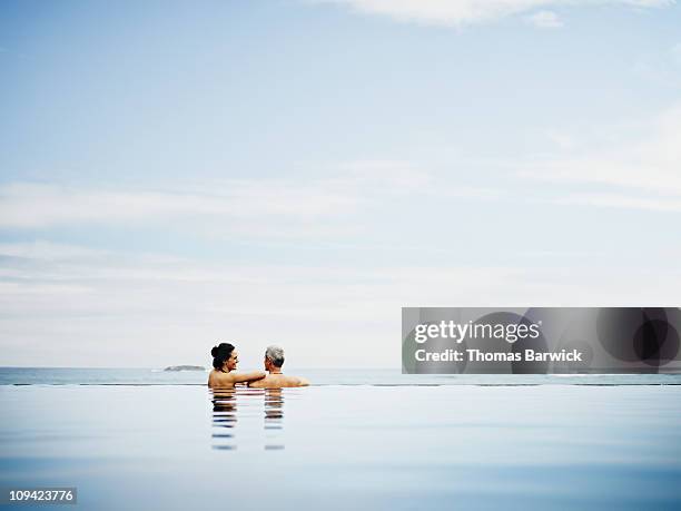 couple embracing on edge of infinity pool - pool mit gegenströmung stock-fotos und bilder