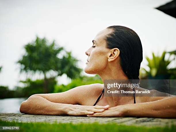 woman at resort resting arms on edge of pool - poolside glamour stock pictures, royalty-free photos & images