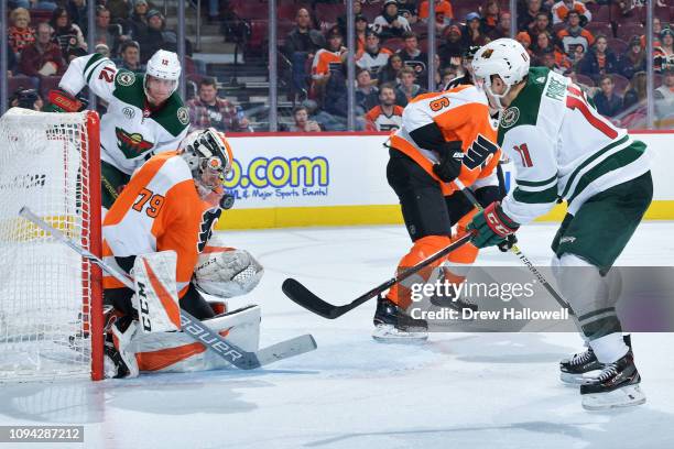 Carter Hart of the Philadelphia Flyers makes a save between Eric Staal and Zach Parise of the Minnesota Wild at Wells Fargo Center on January 14,...