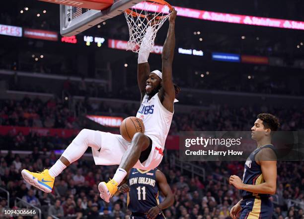 Montrezl Harrell of the LA Clippers dunks in front of Frank Jackson and Jrue Holiday of the New Orleans Pelicans during the first half at Staples...